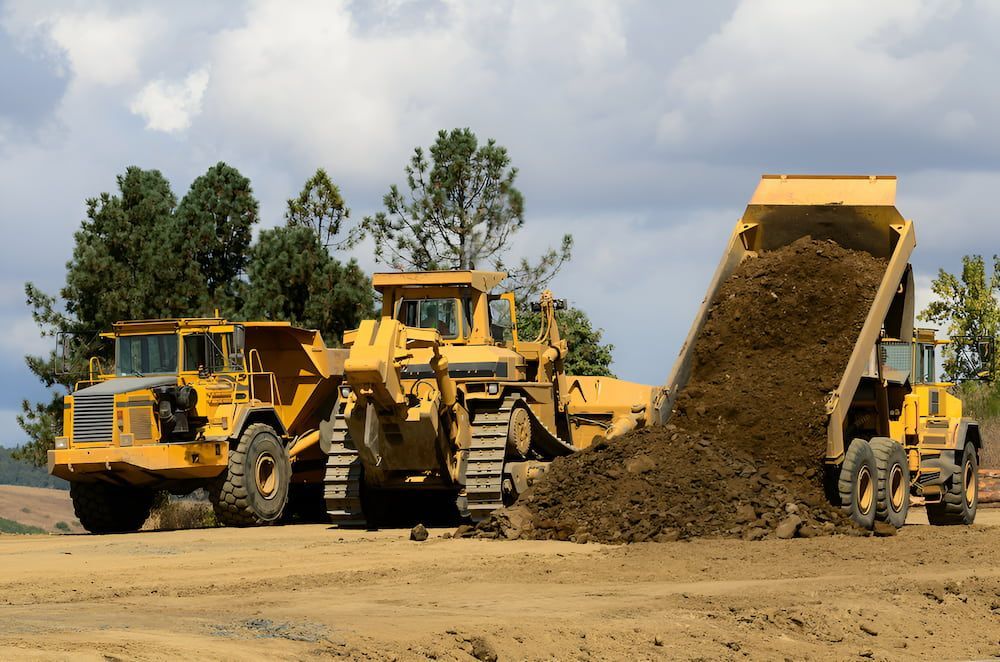 A Dump Truck Is Dumping Dirt Next To A Bulldozer — Jeff Thompson Excavator Hire Pty Ltd In Pink Lily, QLD