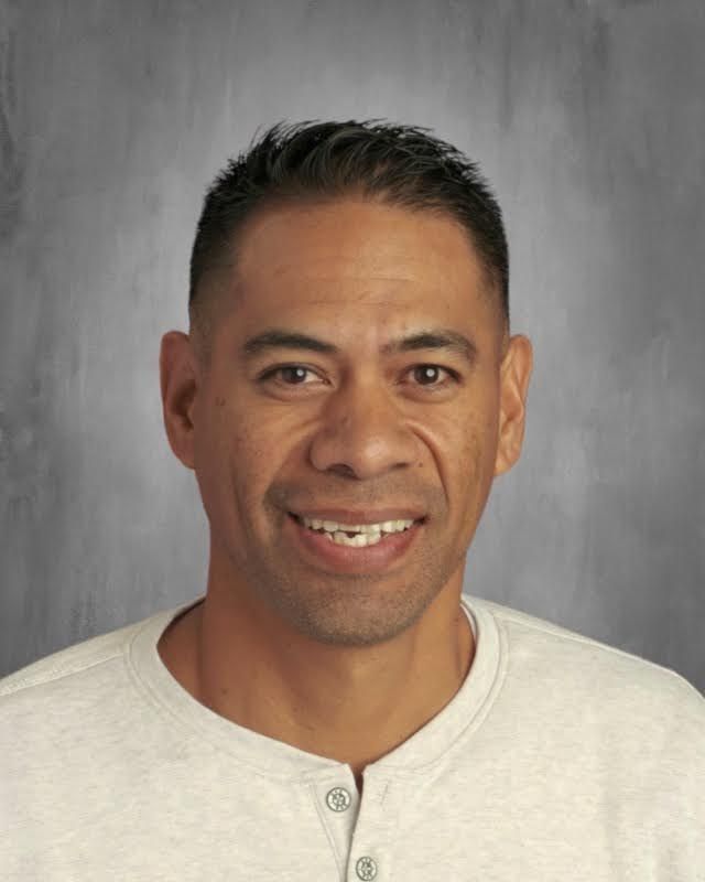 A man in a white shirt is smiling for the camera.