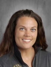 A woman in a black jacket is smiling for the camera.