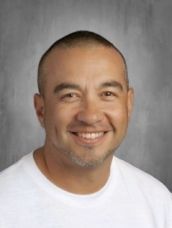 A man in a white shirt is smiling for the camera.