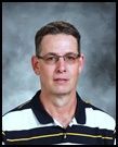 A man wearing glasses and a striped shirt is posing for a picture.
