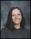 A woman in a gray sweater is smiling for the camera.