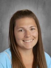 A woman in a blue shirt is smiling for a picture.