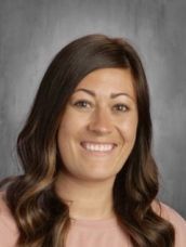 A woman in a pink shirt is smiling for a picture.
