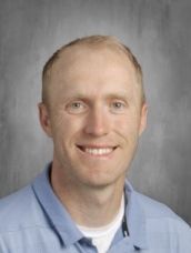 A man in a blue shirt is smiling for the camera.