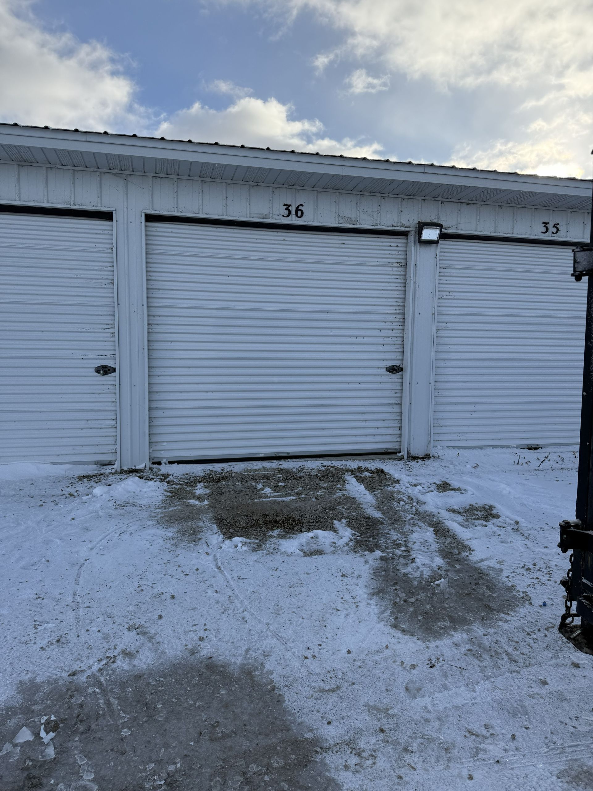 White garage storage units numbered 34 and 35, viewed from a snowy outdoor lot on a bright, cloudy day.