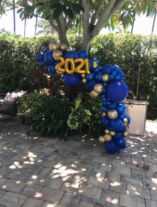 A balloon arch with blue and gold balloons and gold 