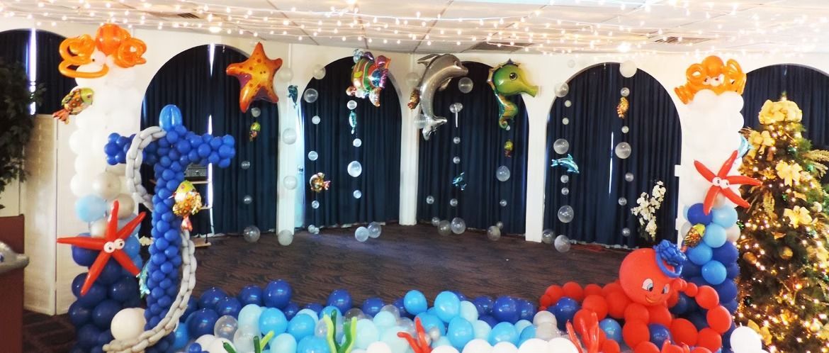 An underwater-themed stage decoration with a balloon seahorse, octopus, sea life balloons, and blue bubble decor.