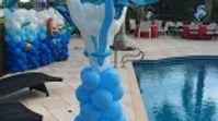 Blue and white balloon decorations, including a column and a large wall display, set up by an outdoor swimming pool.