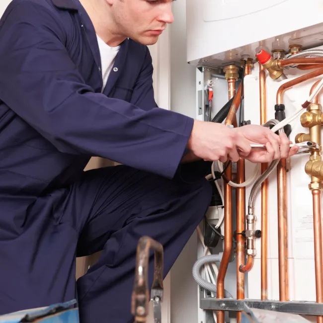 Comfort Air Solution LLC - A man in blue overalls is working on copper pipes