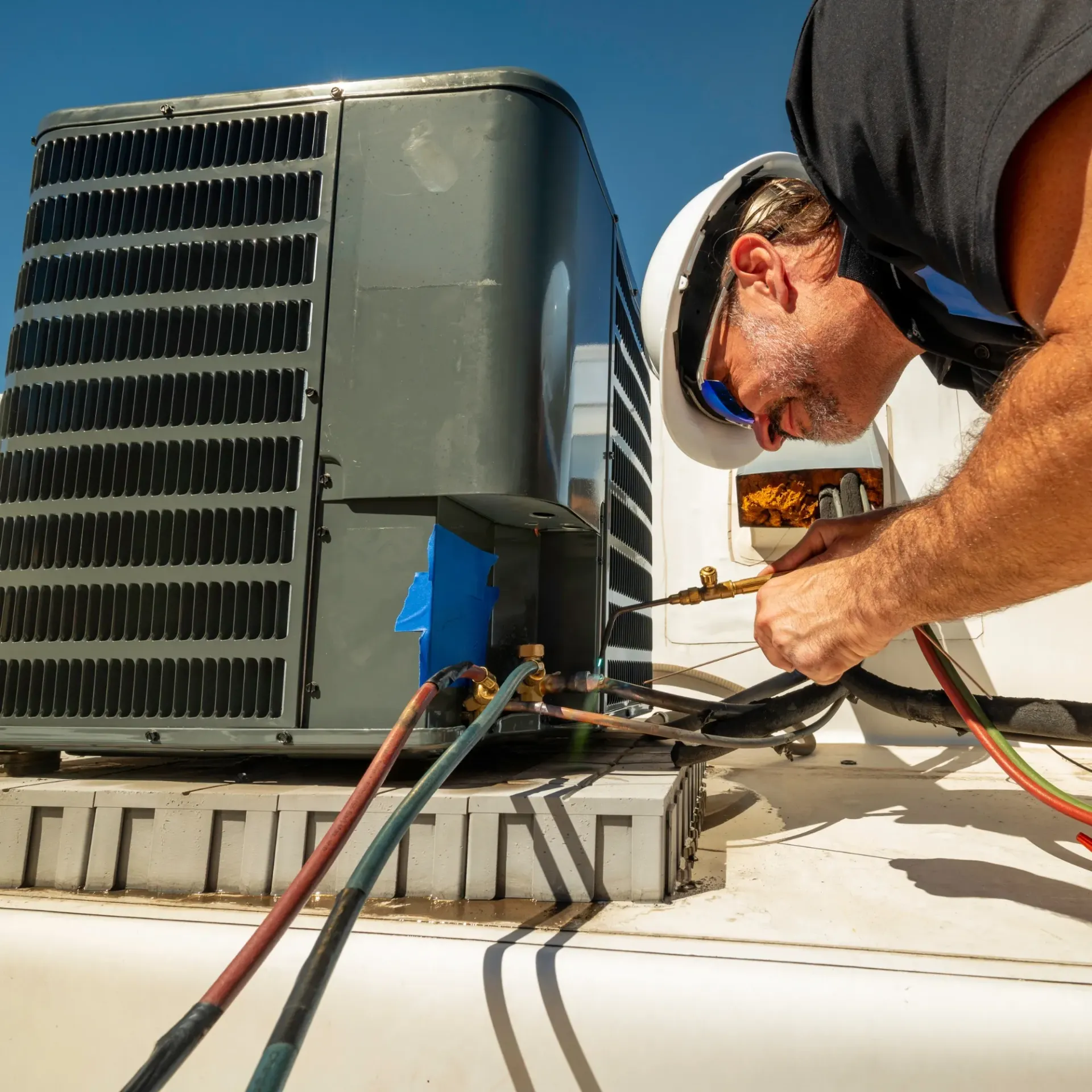 Comfort Air Solution LLC - A man is working on an air conditioner on a roof