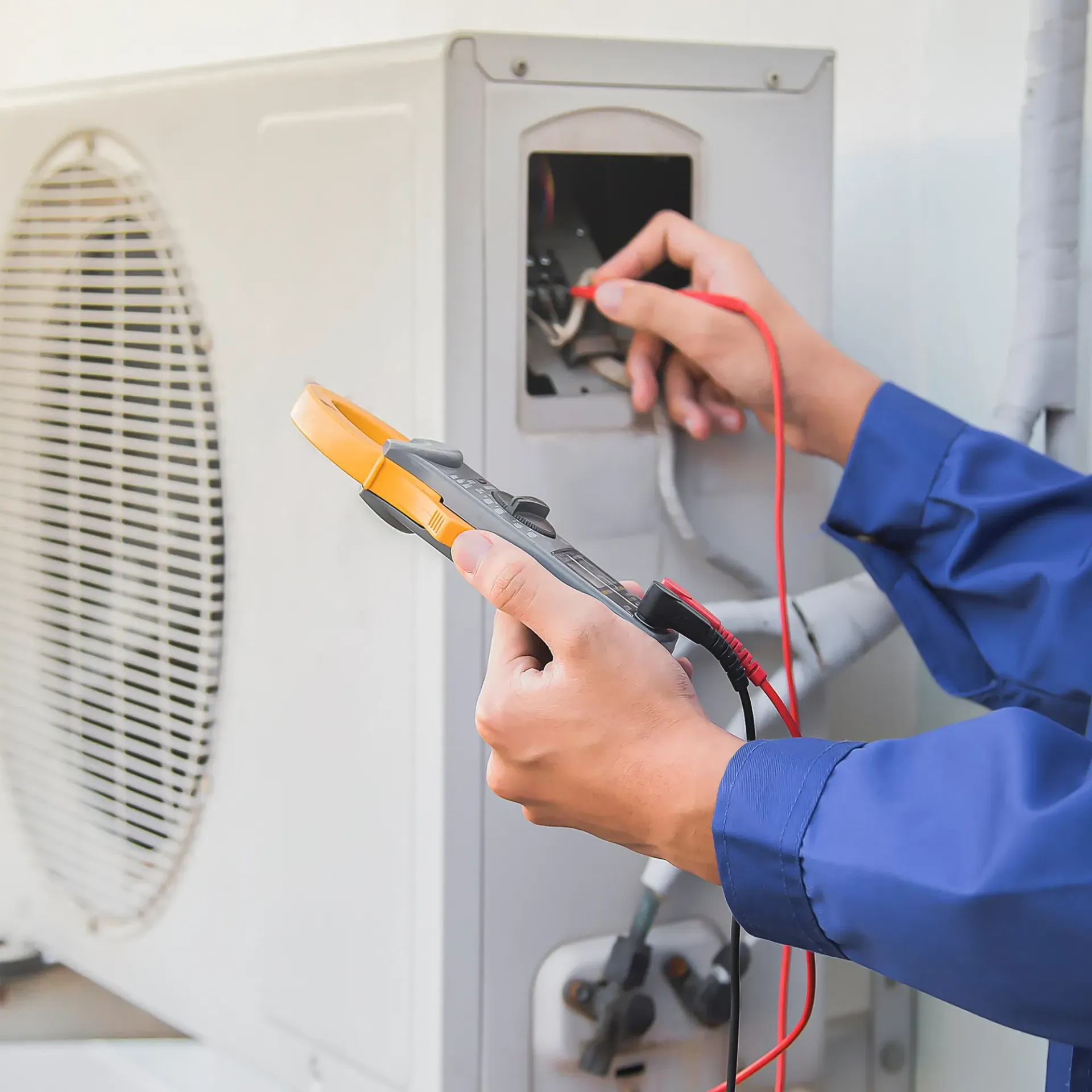 Comfort Air Solution LLC - A person is using a digital multimeter to test an air conditioner.