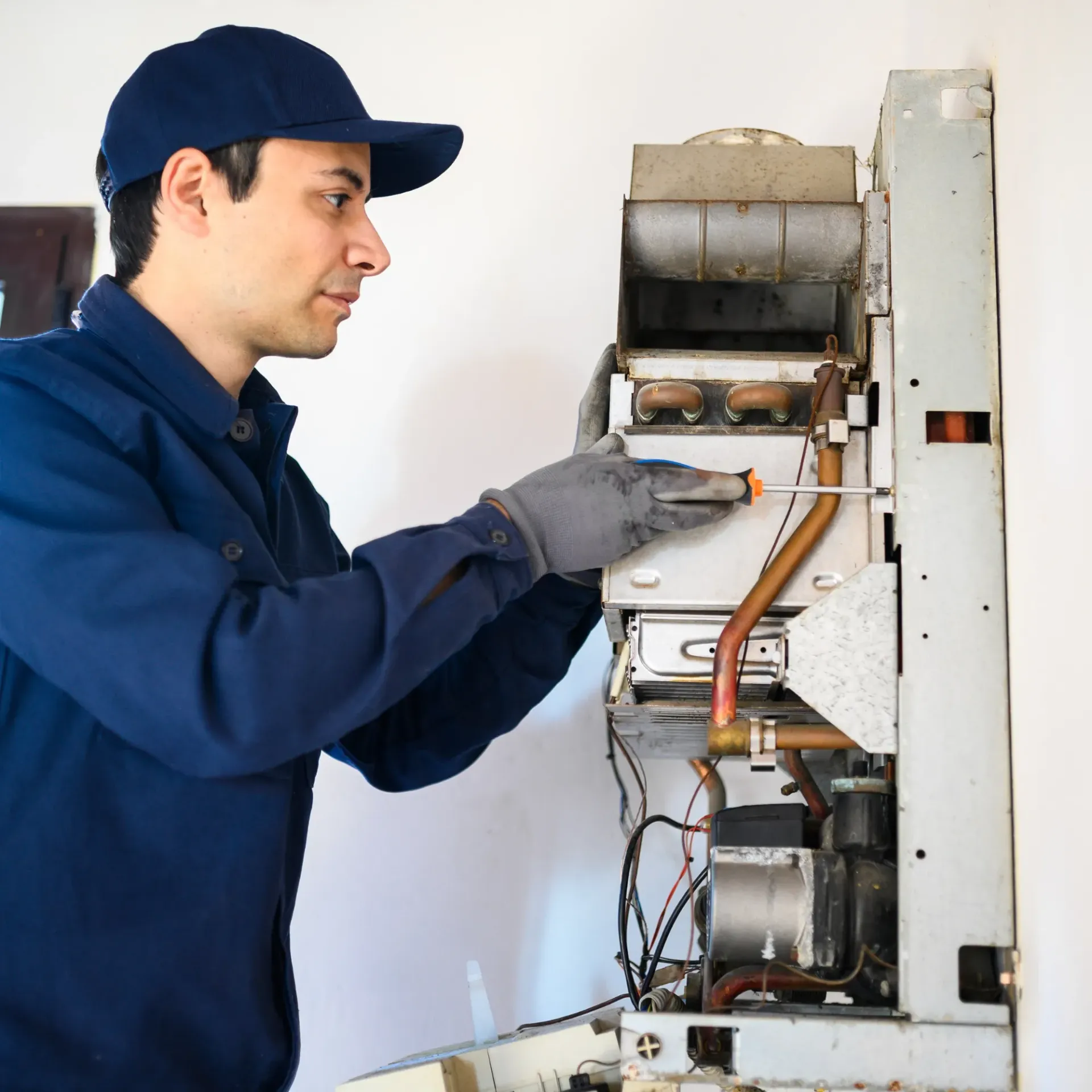 Comfort Air Solution LLC - A man in a blue uniform is working on a boiler