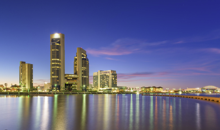 City skyline at dusk with illuminated skyscrapers reflected on calm water City skyline at dusk with illuminated skyscrapers reflected on calm water