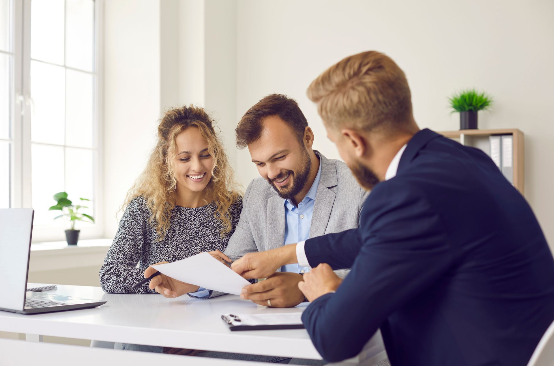 Three colleagues reviewing documents at a desk in a bright office