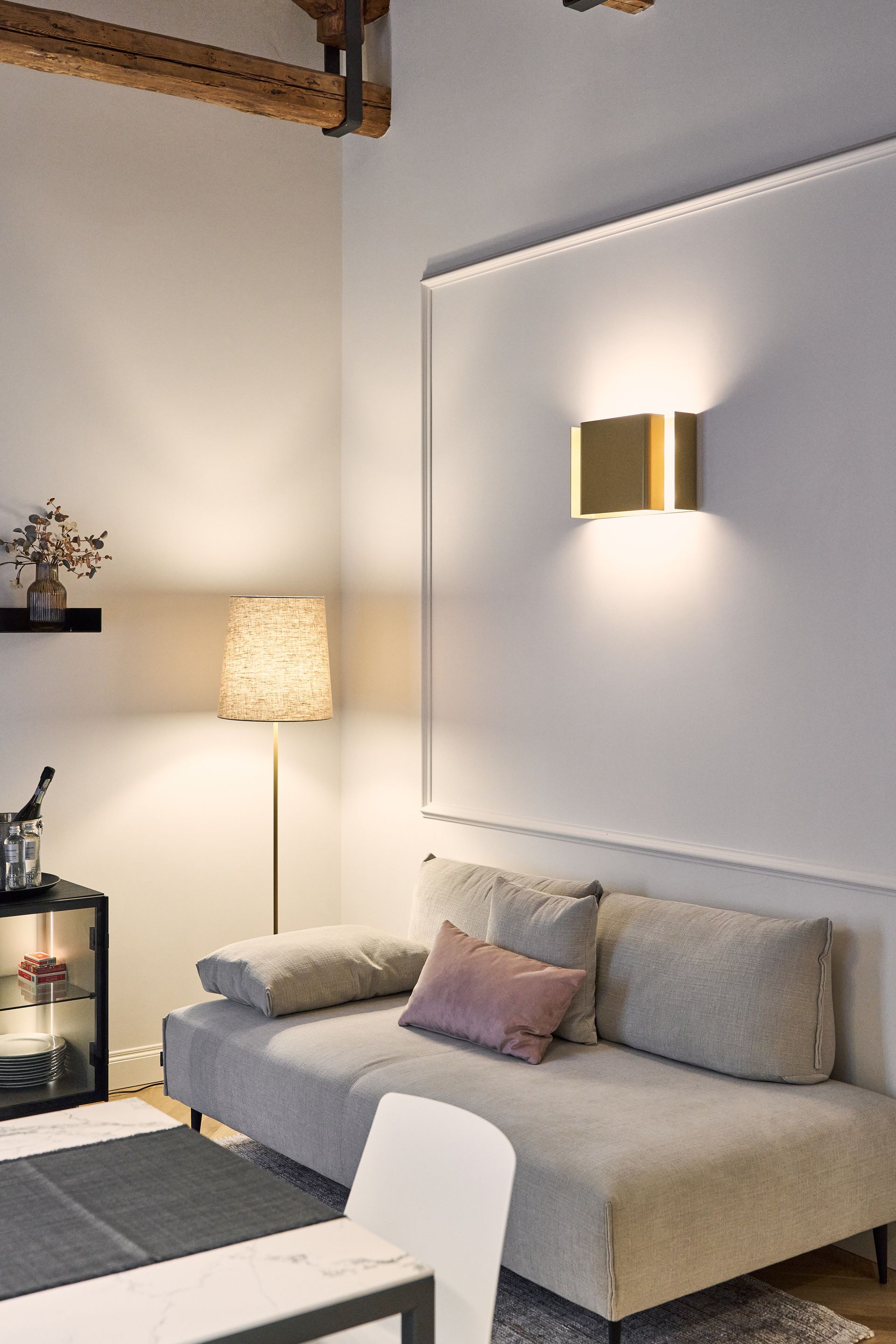 Modern living room with a beige sofa, floor lamp, wall art, and soft neutral lighting.