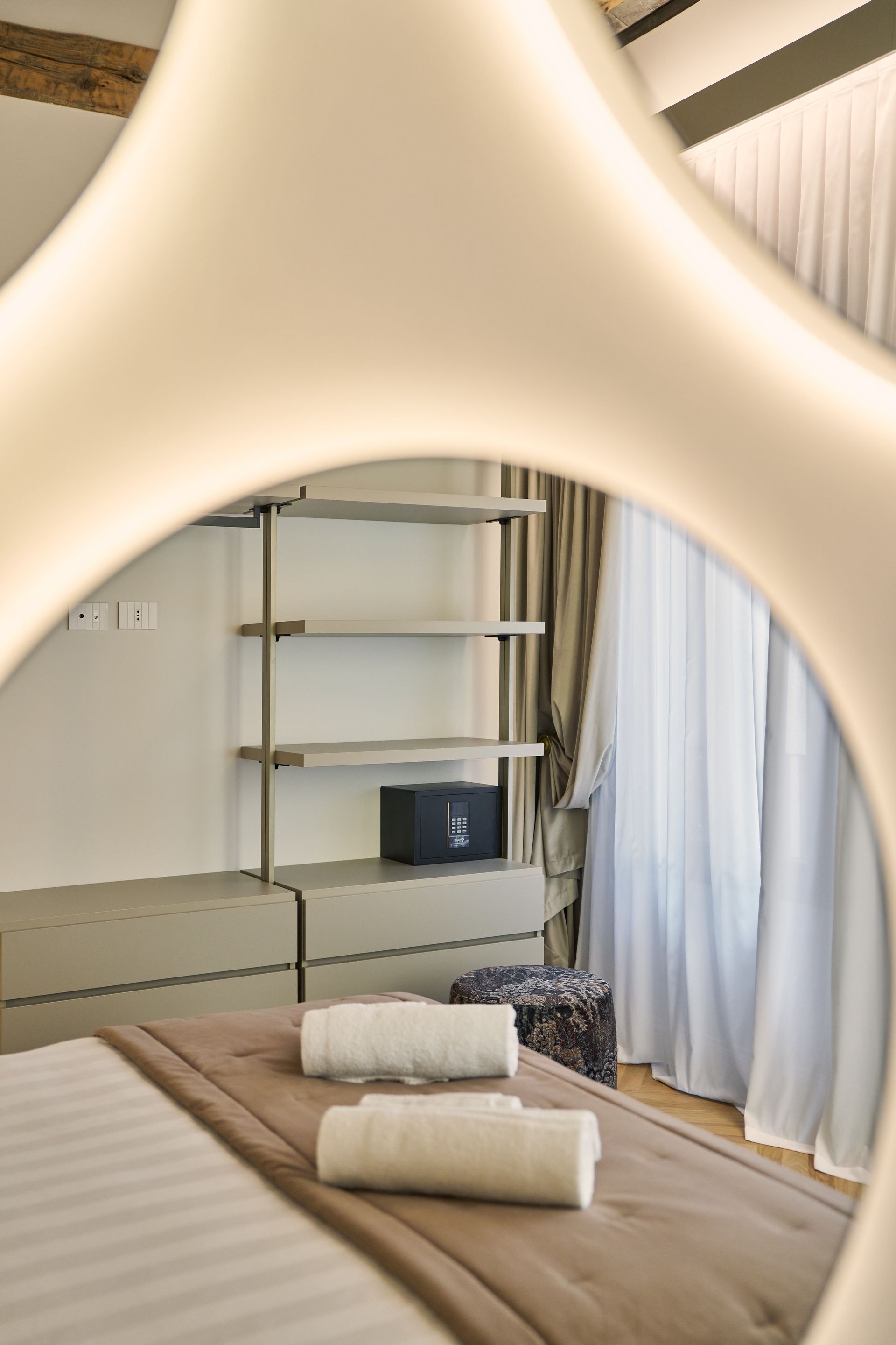 Modern spa treatment room with massage bed, shelving, and sheer curtains