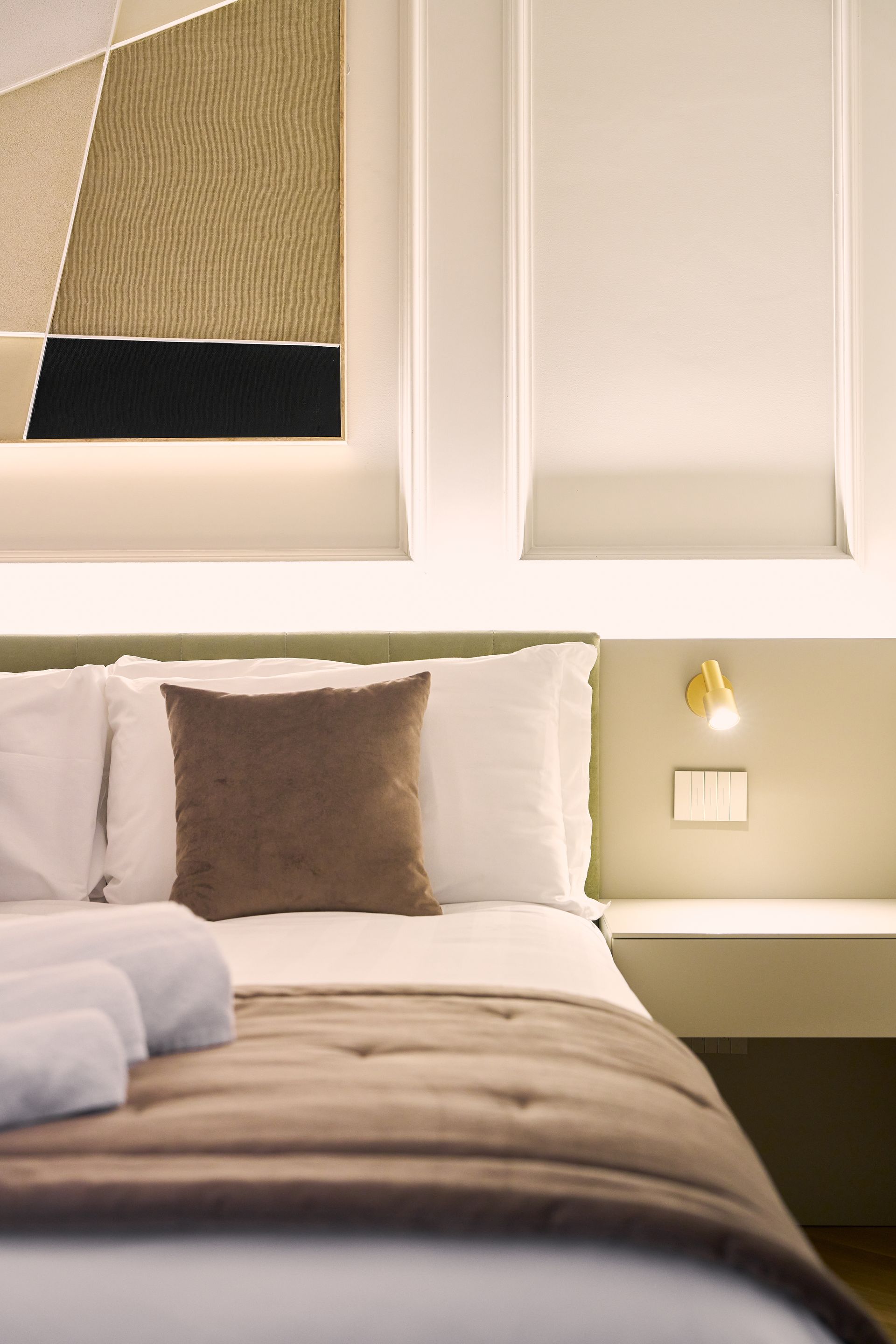 Cozy beige bedroom with a neatly made bed, soft lighting, and a modern headboard backdrop
