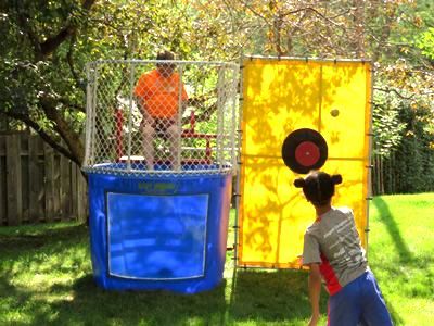 a girl is throwing a frisbee at a target in a dunk tank .