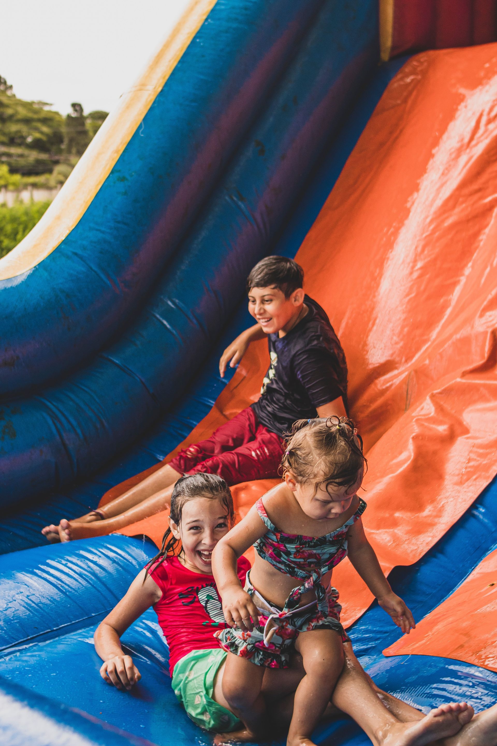 a boy and two girls are playing on an inflatable slide