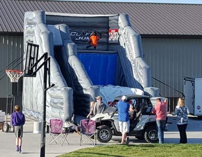 a group of people are standing in front of an inflatable slide .