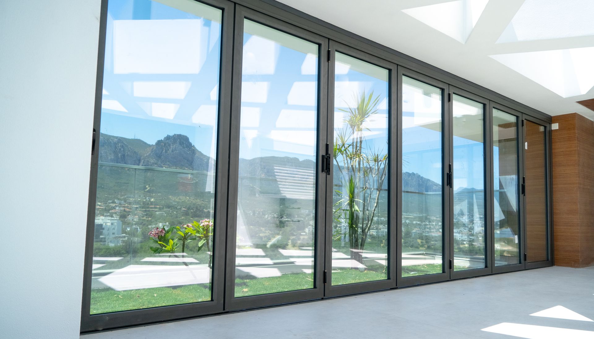 De grandes portes vitrées pliantes donnent sur une montagne et un jardin.