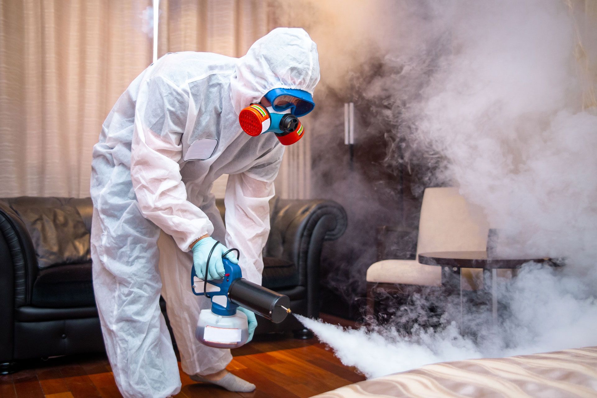 Person in hazmat suit disinfecting a room with fog.