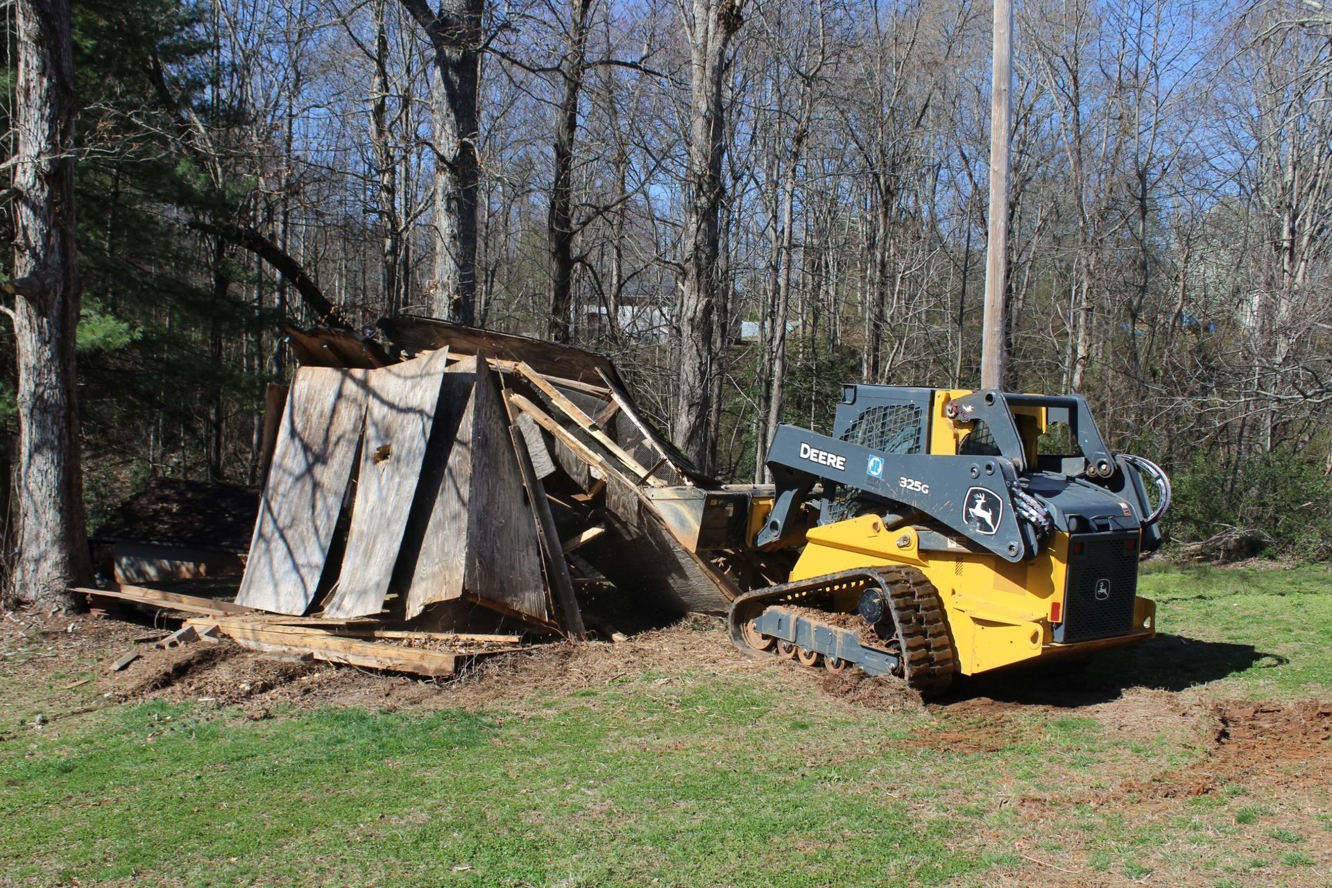 A yellow excavator is demolishing a house.
