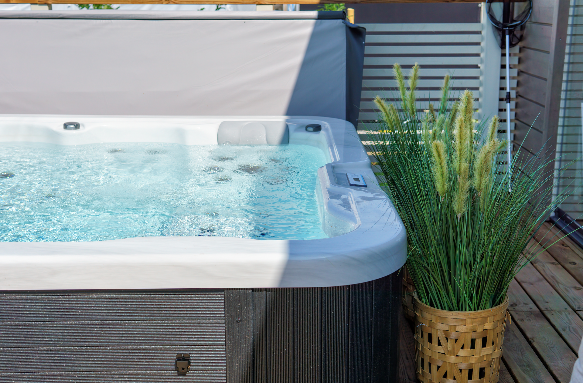 A hot tub is sitting on a wooden deck next to a potted plant.