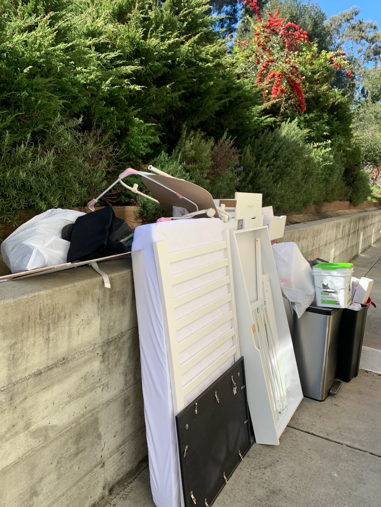 A pile of trash is sitting on the sidewalk next to a wall.