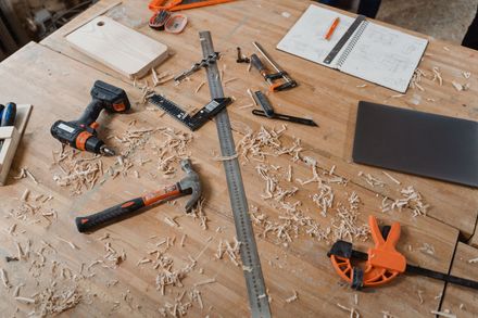 Woodworking tools and wood shavings scattered on a workbench with a measuring square and saw blades