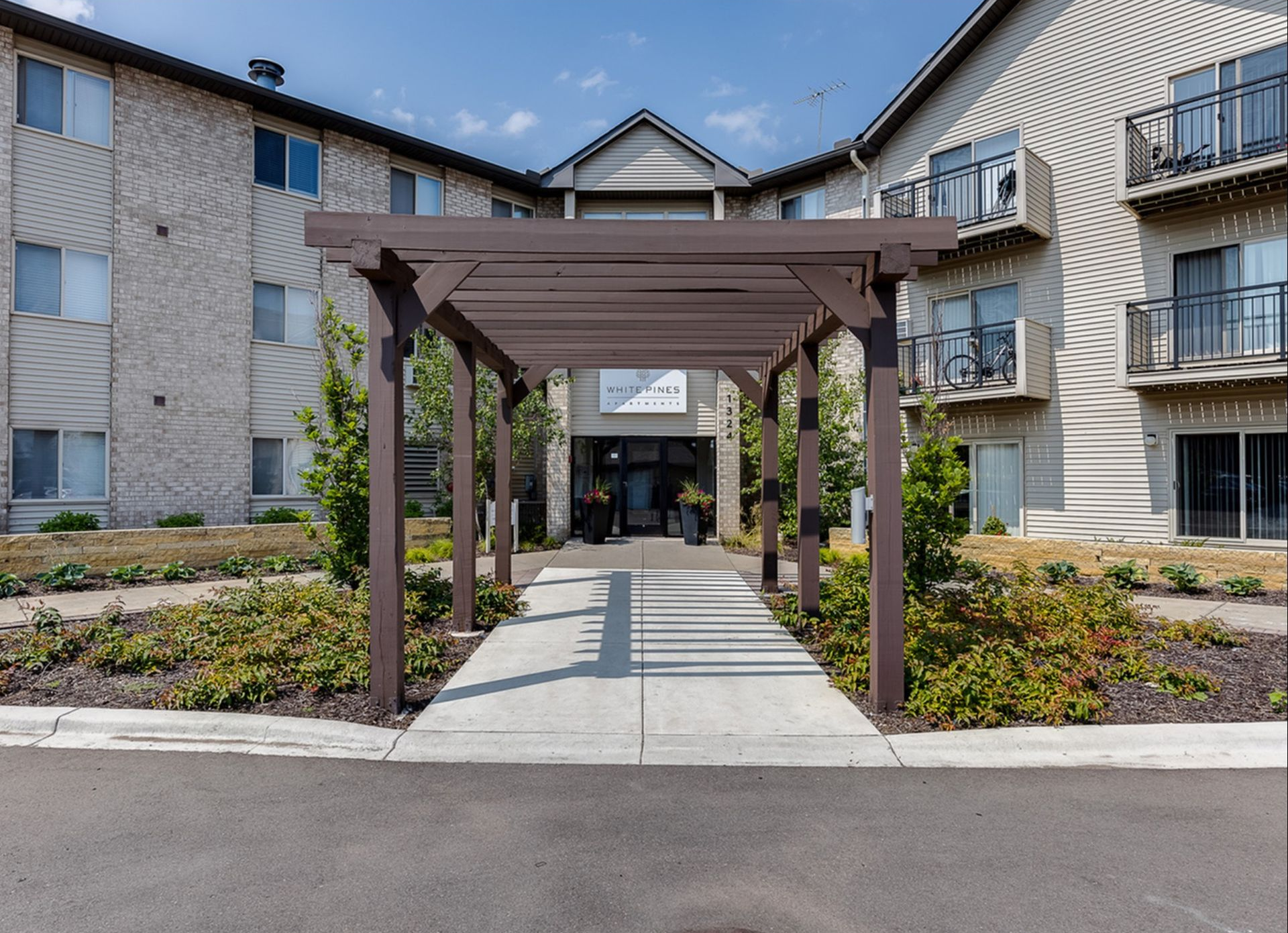 Exterior of a multi-family building with a wooden pergola walkway to the entrance.