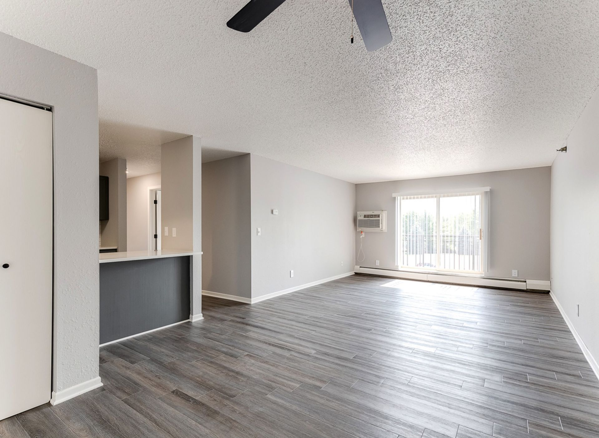 Open living room in a modern apartment with a kitchen bar and sliding balcony door.