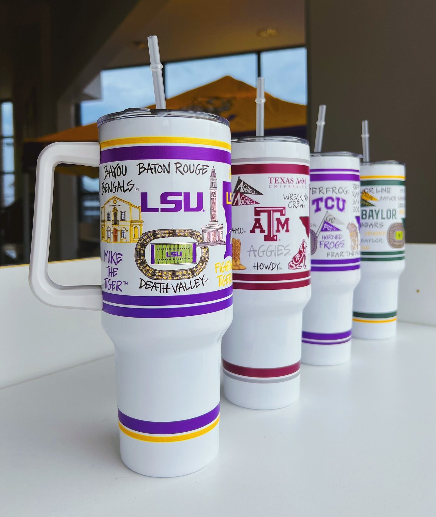 Four stainless steel tumblers with straws are sitting on a table.