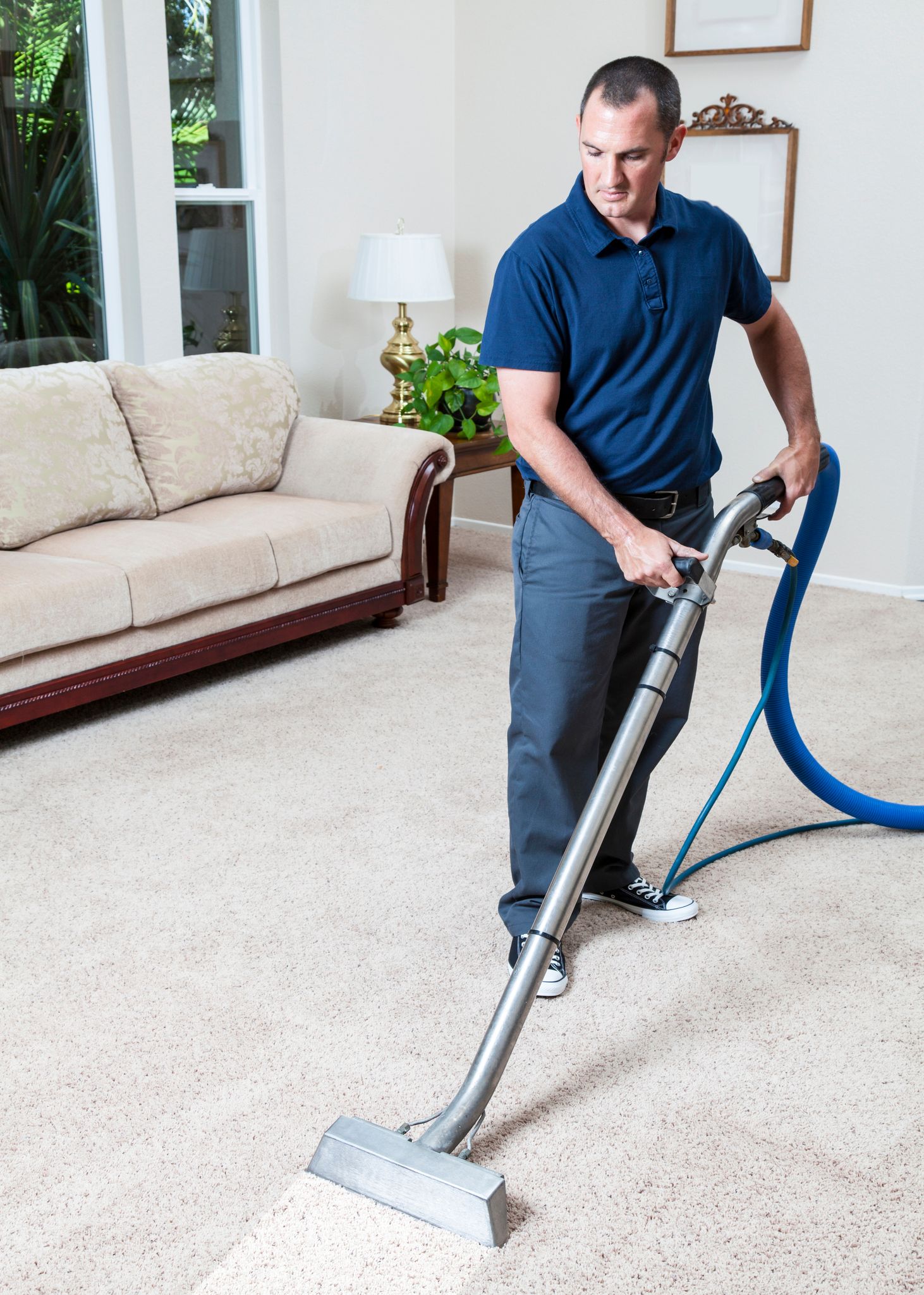 Man using a vacuum cleaner to clean a carpet in a living room