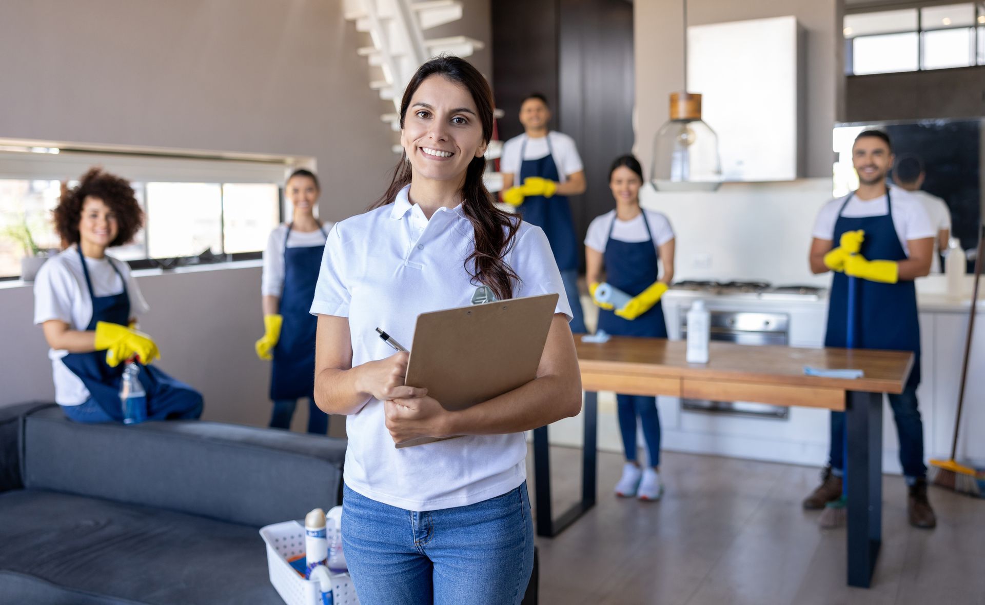 Cleaning crew posing in a modern kitchen, with one woman holding a clipboard in front.