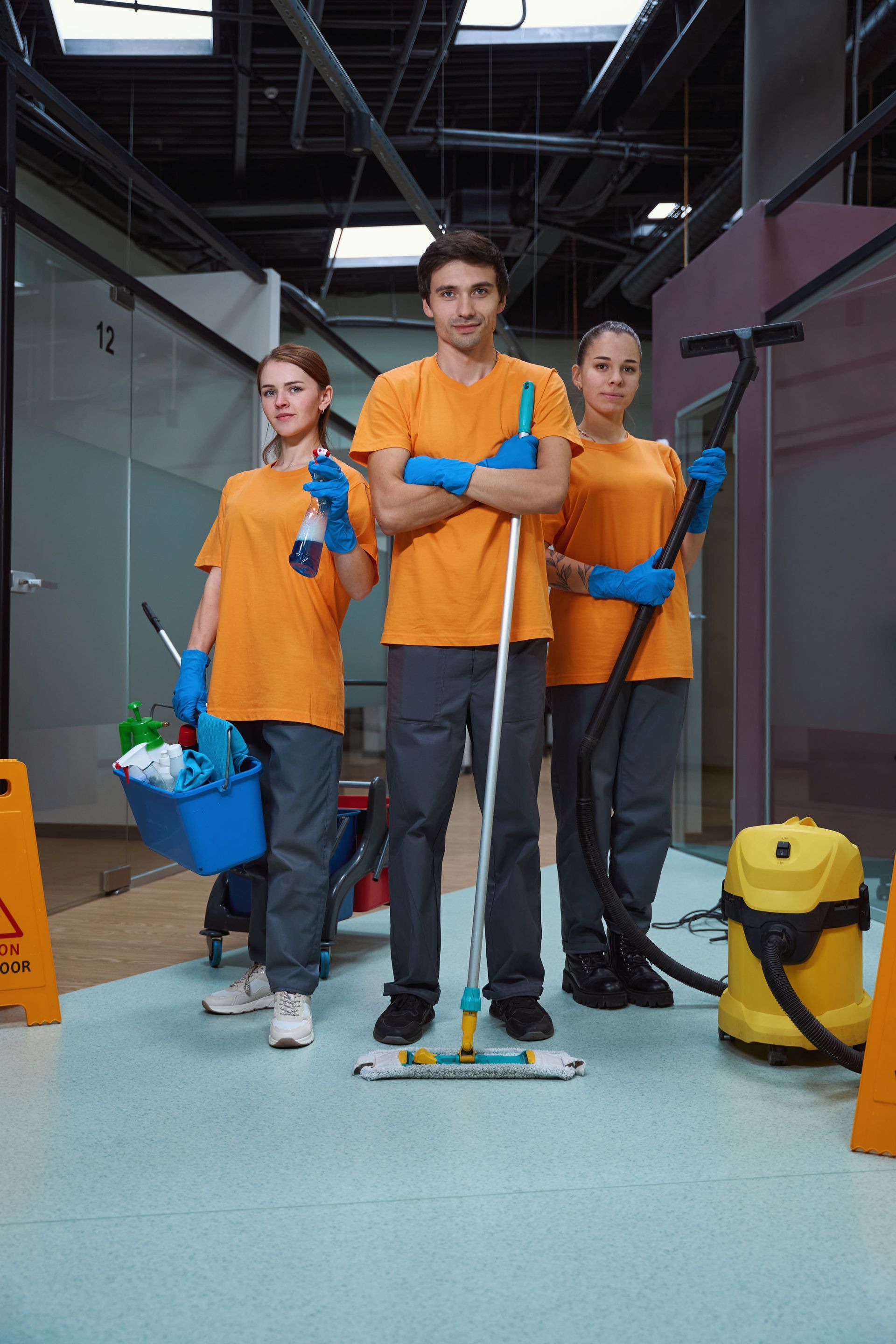 A group of janitors are standing next to each other in an office, commercial cleaning services.