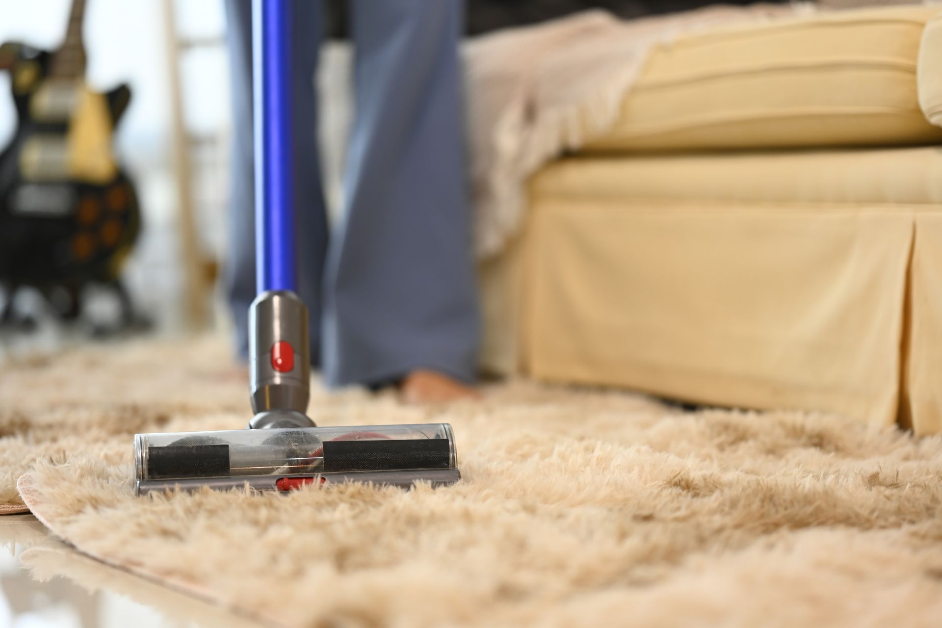 A person is using a vacuum cleaner to carpet cleaner doctor rug in a living room.