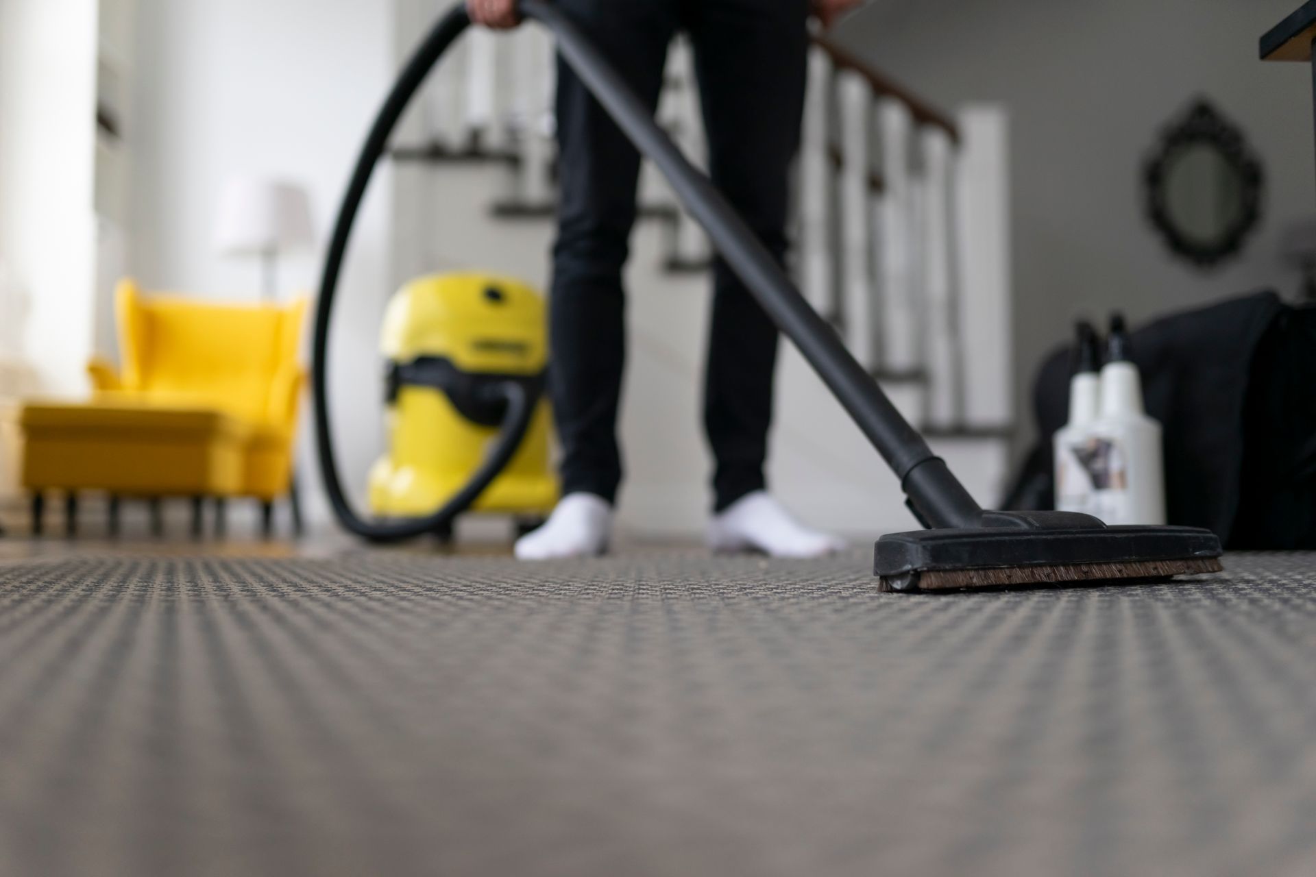 A person is using a vacuum cleaner to clean a carpet in a living room Rug Cleaning