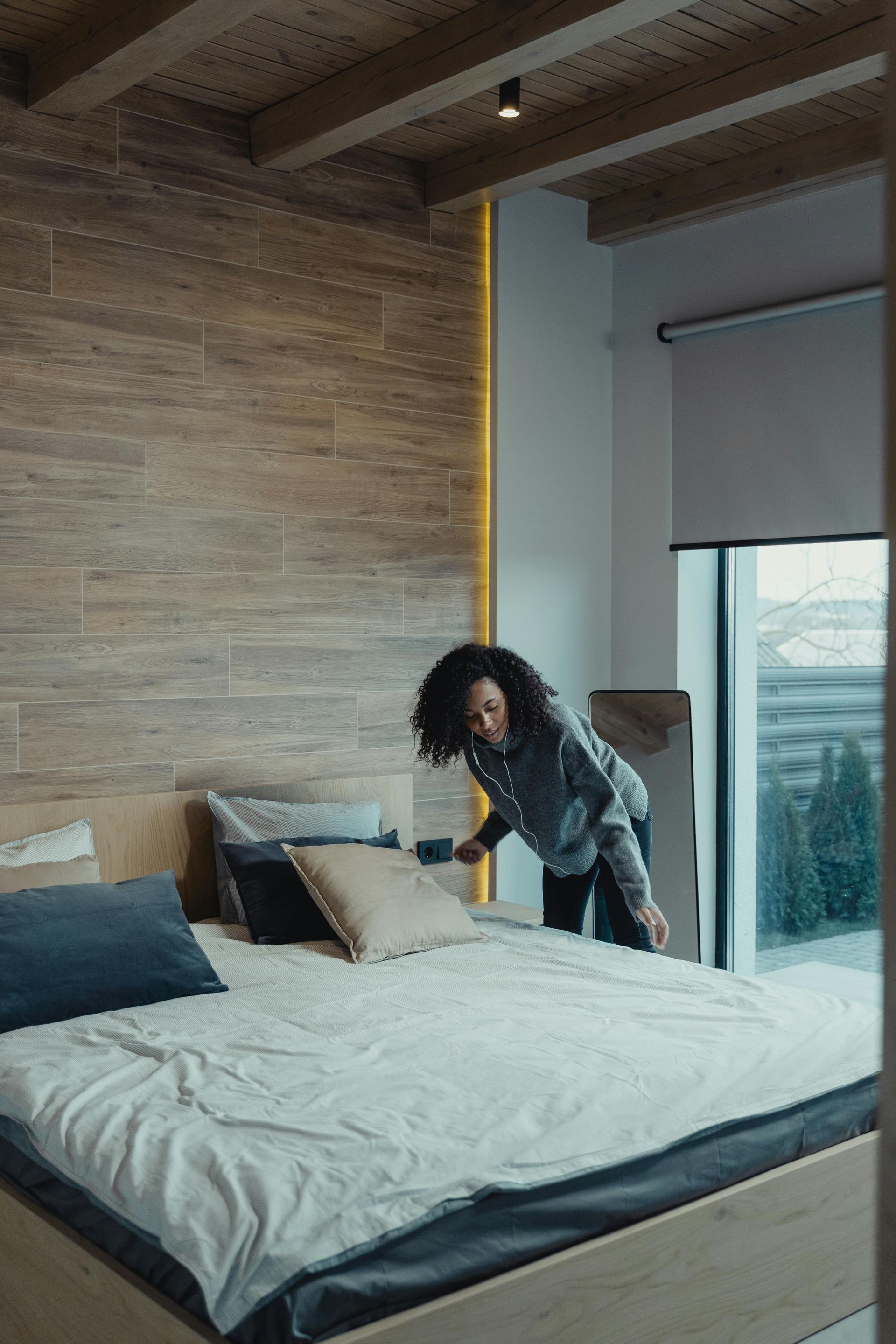 airbnb cleaners a woman is making a bed in a bedroom.
