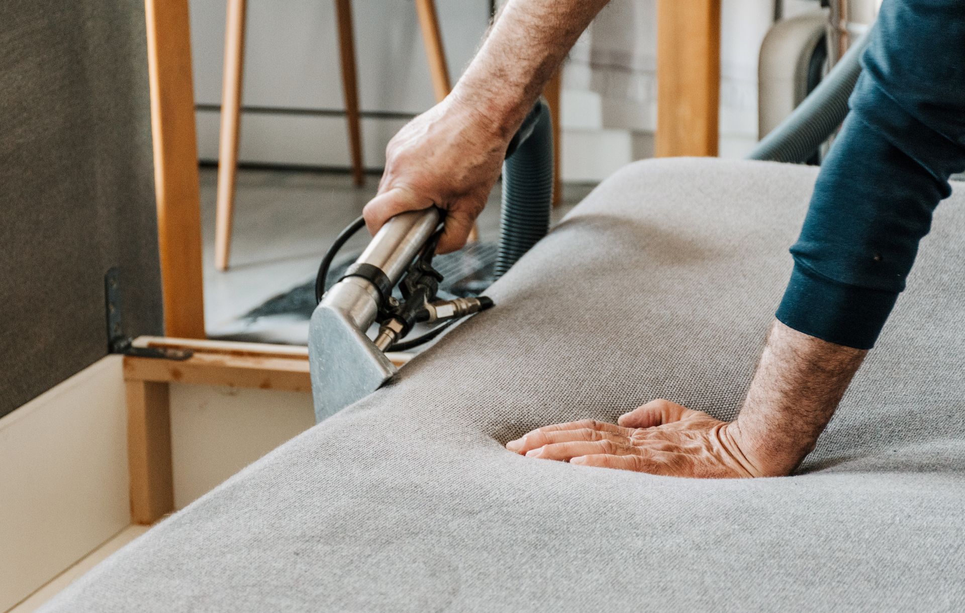 A person is cleaning a couch with a vacuum cleaner.at home upholstery cleaning