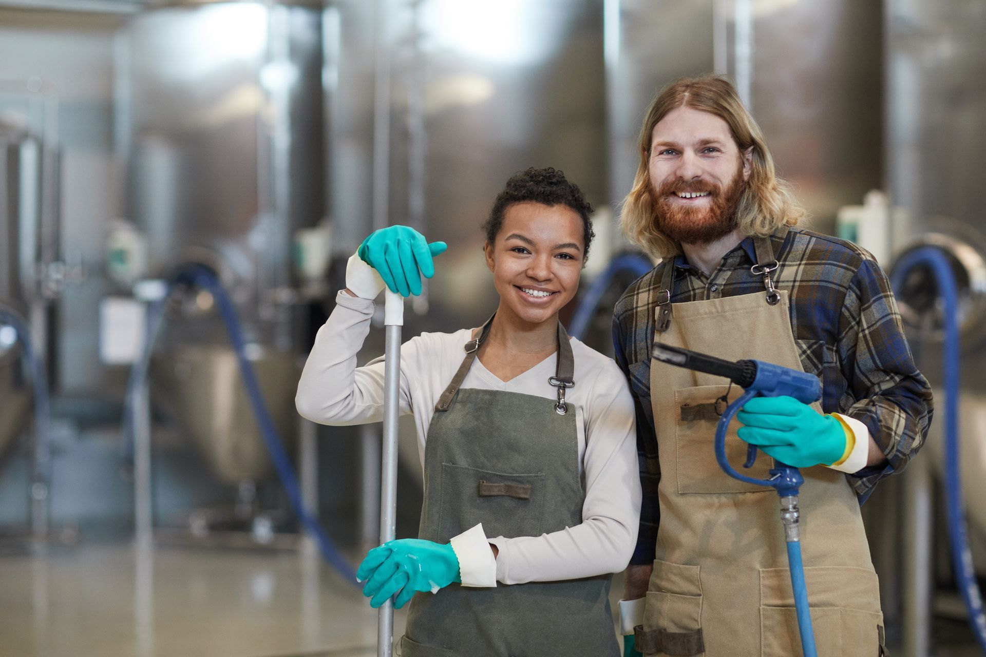 A man and a woman are standing next to each other in a factory holding deeper clean cleaning supplies.