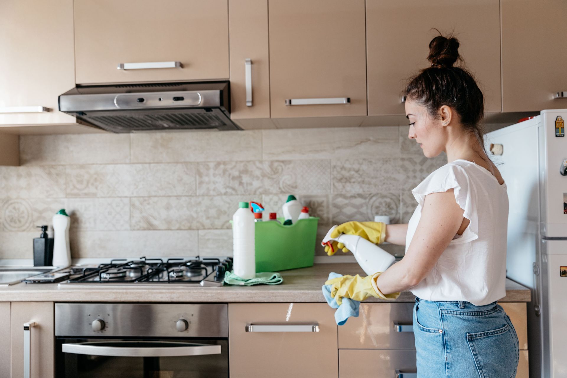 upholstery cleaning A woman is cleaning a kitchen counter with a spray bottle.