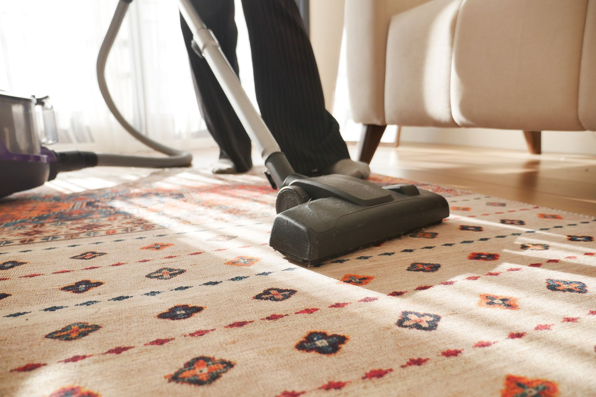 A person is vacuuming a rug in a living room. commercial office cleaning services