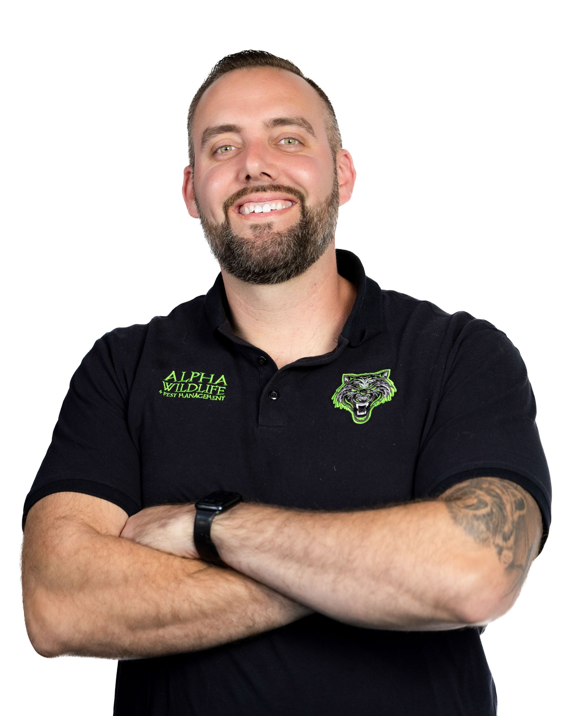 Smiling man in a black polo shirt with green logos, arms crossed on a white background