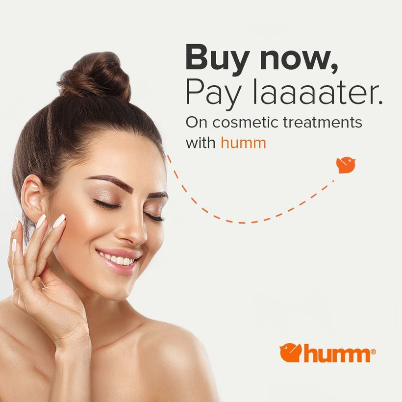 A woman is smiling and touching her face.