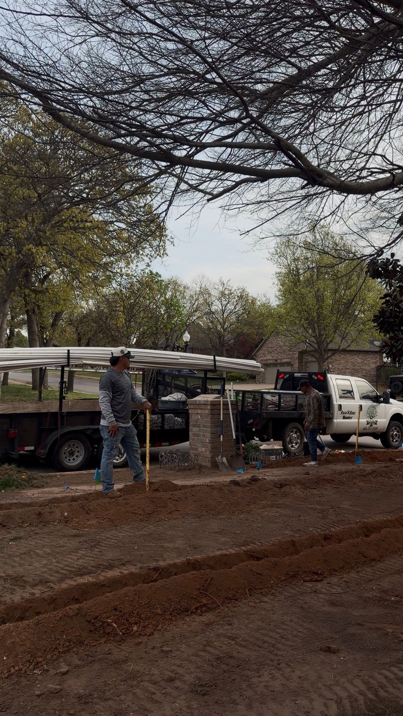 Safari vehicles and people gathered on a dirt road under trees, with a white truck nearby.
