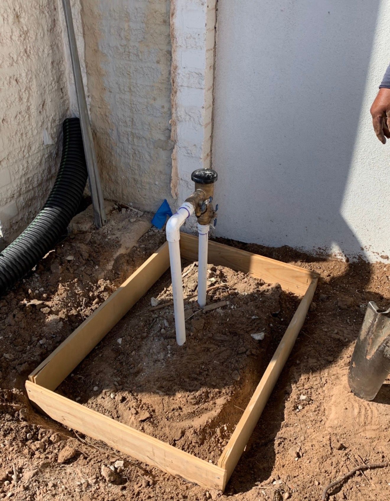 Plumbing stub-out with pipes and valve inside a wooden frame at a construction site