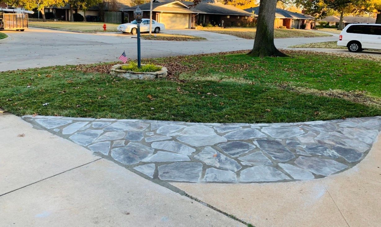Stone-paved driveway apron beside a lawn and mailbox in a suburban front yard