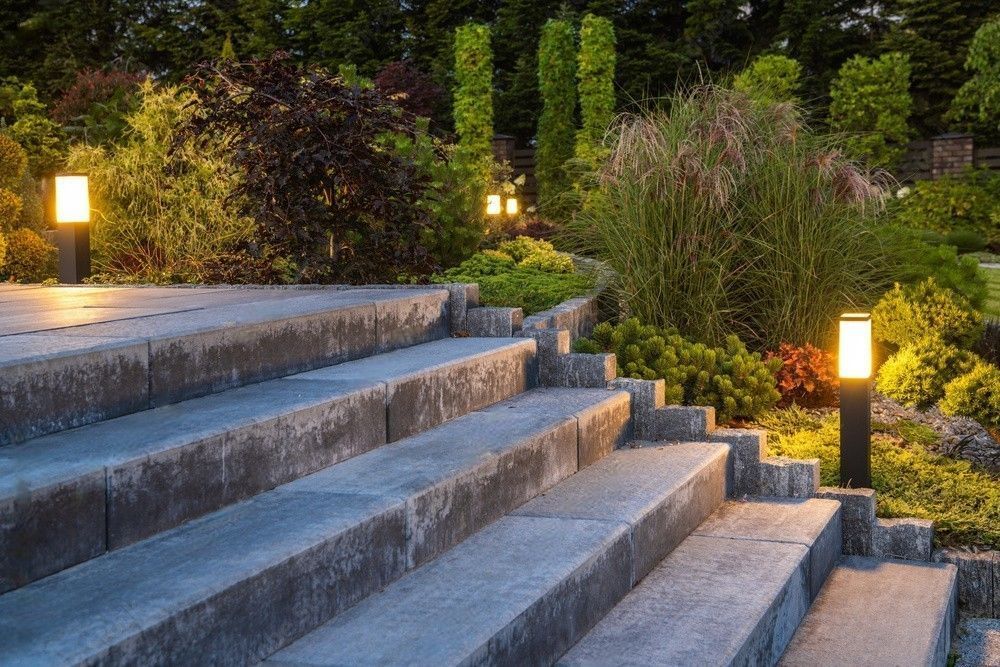 Stone steps in a landscaped garden lit by warm pathway lights at dusk